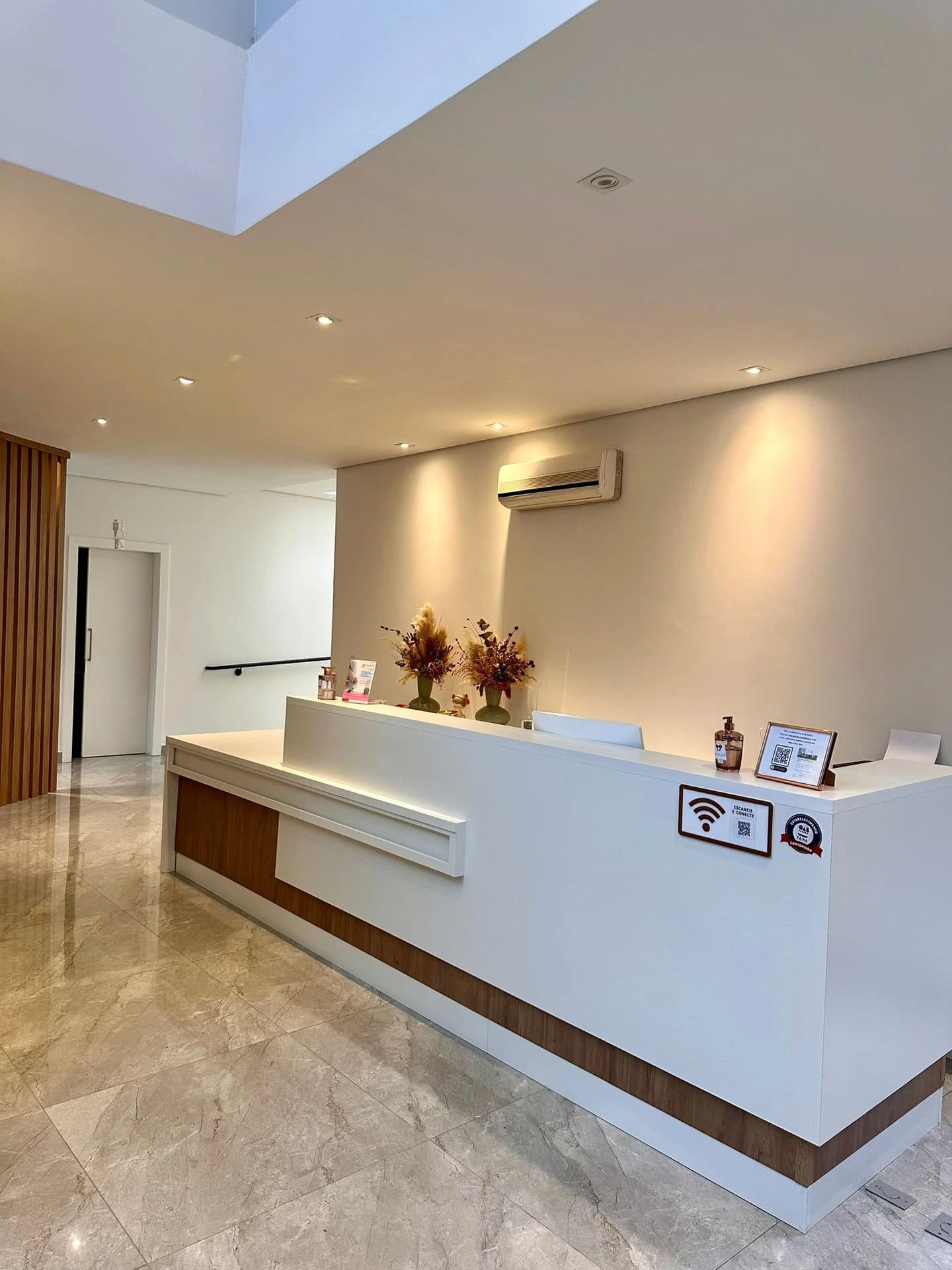 Recepção da Clínica Vittalice — balcão claro, plantas e iluminação aconchegante